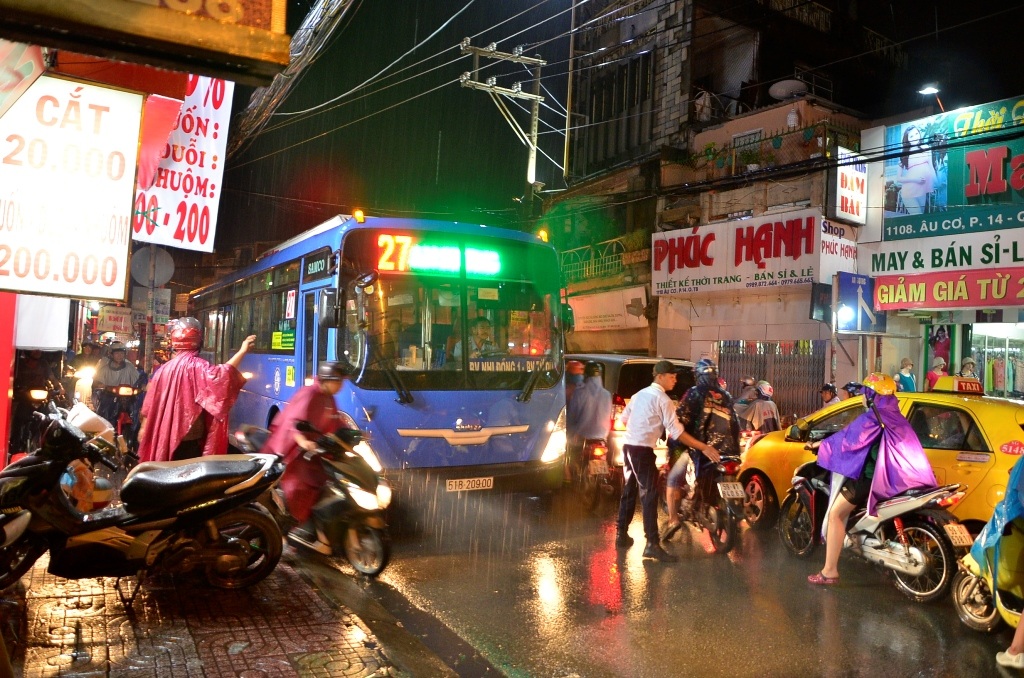 Một người đàn ông đứng giữa mưa để điều tiết giao thông