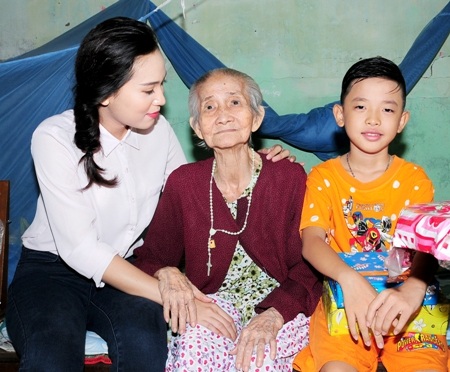 Hoa khôi Nguyễn Thùy Trang ân cần thăm hỏi sức khỏe của một cụ già.