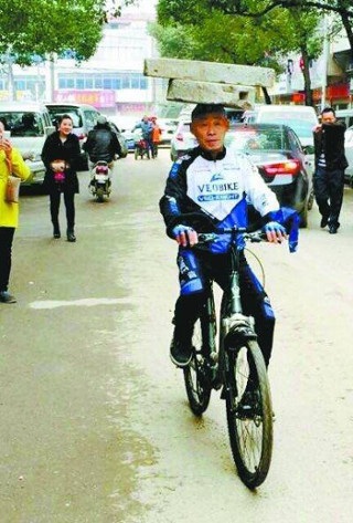 Giảm 30kg nhờ đội đá lên đầu hàng ngày - 6 Trong khi đó, một người đàn ông 52 tuổi khác đến từ Vũ Hán, lại thể hiện khả năng cân bằng của mình, khi đầu đội khối đá và lái xe đạp.