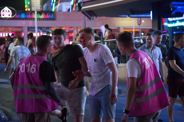 Một nam thanh niên mặt bê bết máu sau vụ ẩu đả đang đứng phân trần với nhân viên bảo vệ.