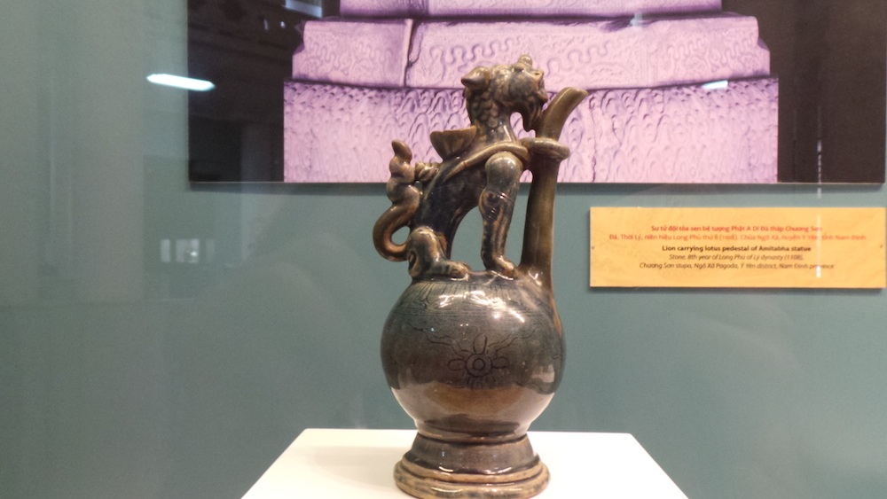 Bình rót có quai hình nghê, chất liệu gốm mem lam xám thời Mạc thế kỷ 16. Là loại đồ thờ dùng để đựng nước, rượu cúng, hình thức này chỉ xuất hiện dưới thời nhà Mạc.