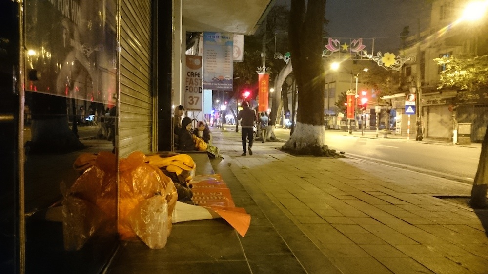 Dọc vỉa hè phố Tràng Thi, một người phụ nữ và hai đứa trẻ nhỏ nằm lăn lóc trên vỉa hè. Thi thoảng có những người mang cho áo rét, cháo hay mì tôm.