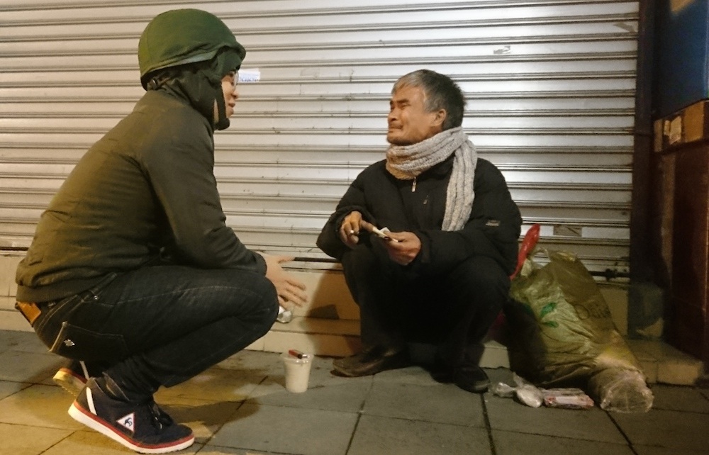 Một tình nguyện viên đang giúp đỡ một ông cụ trên phố Tràng Thi.