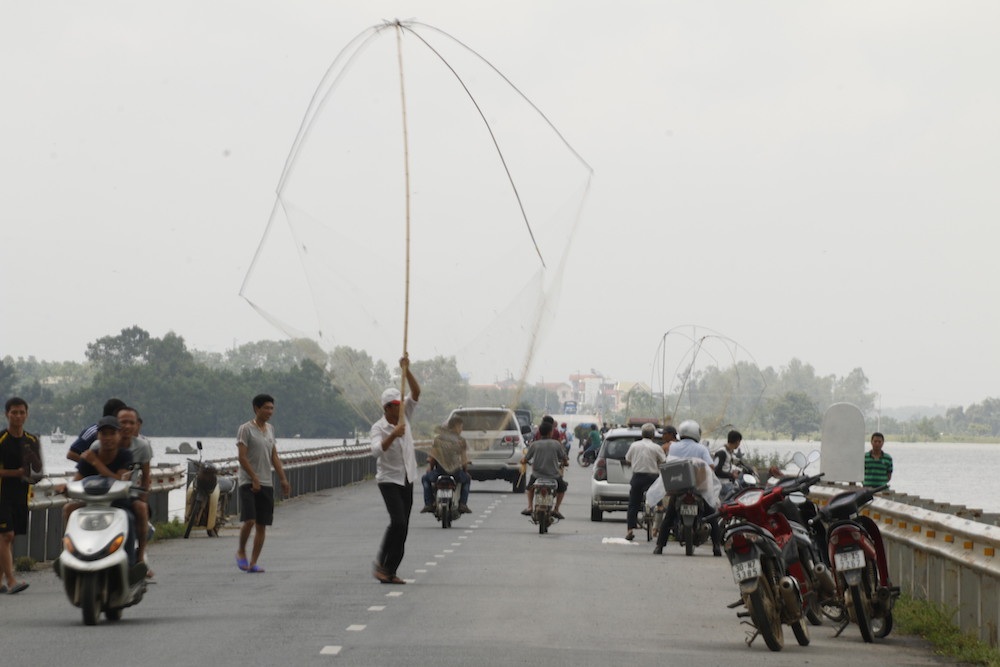 
Hai bên đường, người dân rủ nhau bắt cá. Ngư cụ chủ yếu là vó (chũm), câu, lưới tơ.

