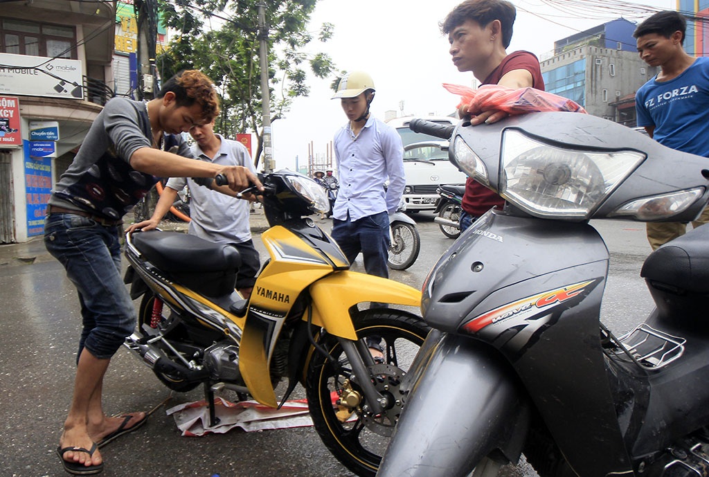 
Thợ sửa xe máy làm việc luôn tay, hết xe này lại đến xe khác.
