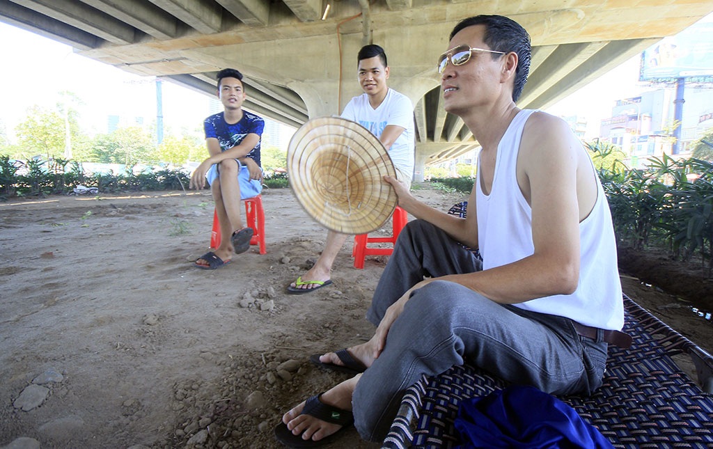 
Một số người chọn cách kê ghế nghỉ ngơi dưới gầm cầu đường trên cao (Ảnh chụp trên đường vành đai 3).
