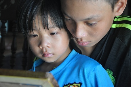 Hai anh em chăm chú nhìn tấm di ảnh của bố mẹ.