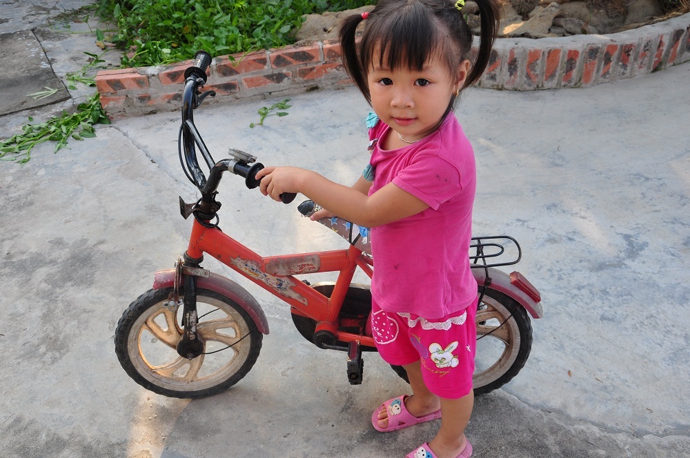 Cháu Tuyết với chiếc xe đạp đồng nát bà mua cho. Chiếc xe không đi được, chỉ để dắt đi chơi.