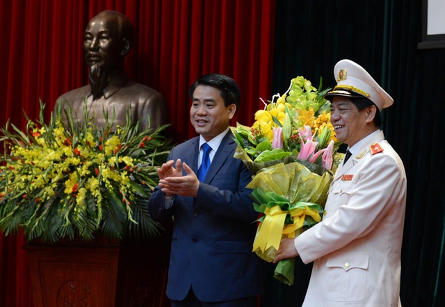 Tân Giám đốc Công an Hà Nội Đoàn Duy Khương nhận bó hoa chúc mừng từ người tiền nhiệm - Thiếu tướng Nguyễn Đức Chung - Phó Bí thư Thành ủy, Chủ tịch UBND Thành phố Hà Nội. (Ảnh: Mạnh Thắng).