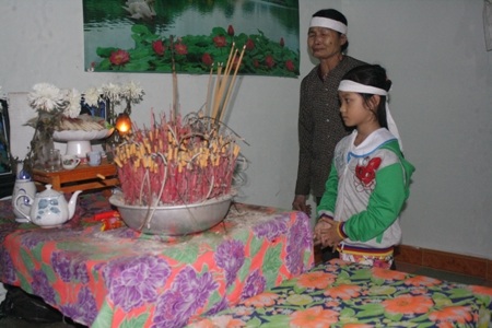 Cháu Như cùng bà nội trước bàn thờ bố mẹ