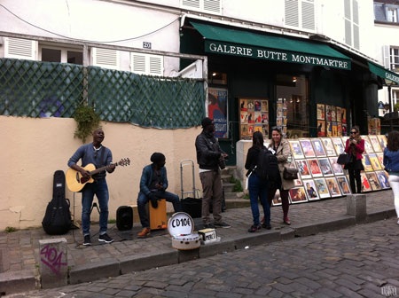 Âm nhạc đường phố Paris - Nét thi vị quyến rũ của "kinh đô ánh sáng" - 4 Nhóm nhạc chơi ở quảng trường nhỏ sau nhà thờ Thánh Tâm và 2 nữ du khách đang mua album của họ