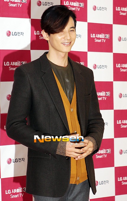 Won Bin mặc vest kiết hợp với áo len có phần nghiêm nghị.