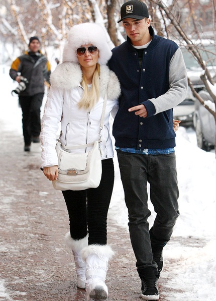 Paris Hilton ăn vận như một nàng công chúa tuyết với áo phao trắng, bốt trắng và túi xách cùng màu.