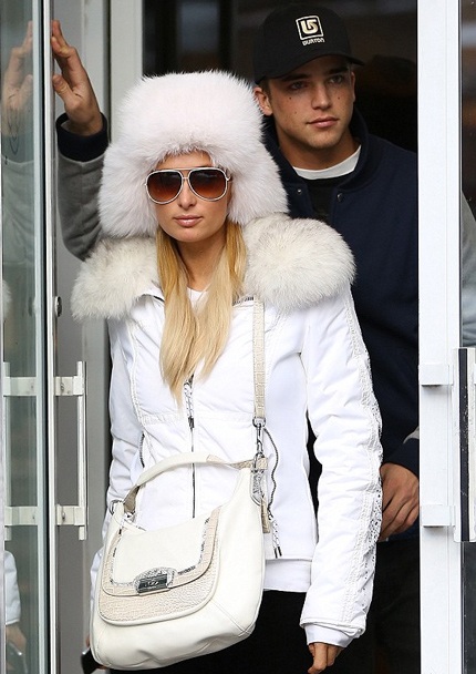 Paris Hilton ăn vận như một nàng công chúa tuyết với áo phao trắng, bốt trắng và túi xách cùng màu.