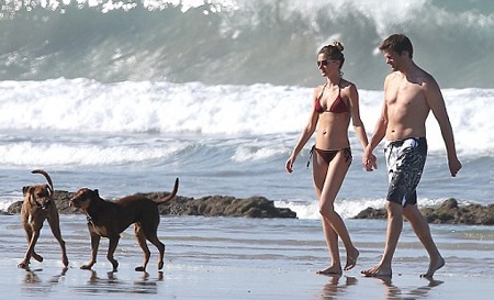 Siêu mẫu bế cô con gái 1 tuổi trên tay trong khi chồng cô đang phô diễn khả năng chơi thể thao.