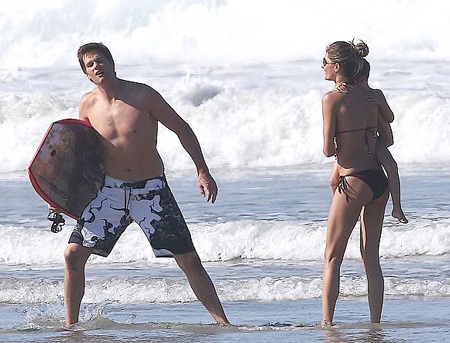 Siêu mẫu bế cô con gái 1 tuổi trên tay trong khi chồng cô đang phô diễn khả năng chơi thể thao.