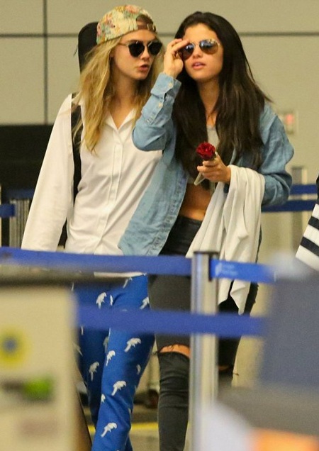 Nữ ca sĩ 22 tuổi cầm theo một bông hồng đỏ trên tay trong khi Cara khệ nệ bê đồ.