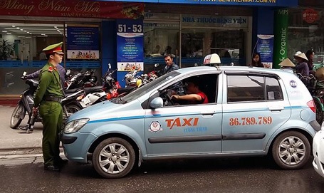 Hà Nội: Cảnh sát bám cần gạt nước xe taxi - 1 Binh nhất Lê Quốc Bảo chặn đầu xe, yêu cầu lái xe xuất trình giấy tờ (Ảnh: CTV).