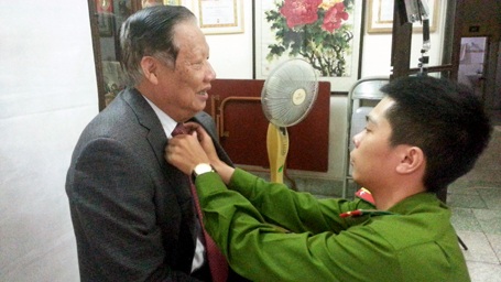 Công an Hà Nội vào tận… giường làm chứng minh thư cho dân - 4 Chỉnh sửa trang phục trước khi chụp ảnh cho cụ Lê Huy Ngọ, nguyên Bộ trưởng Bộ NN&PTNT.