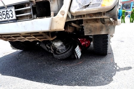 Chiếc xe máy bị dính chặt dưới gầm bánh trước xe chở bê tông