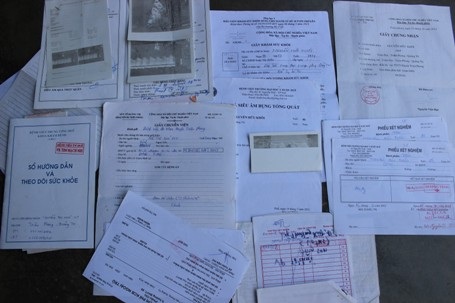 Chồng giấy tờ, bệnh án, phiếu khám liệt kê bệnh tật của anh Khôi và cháu Ny