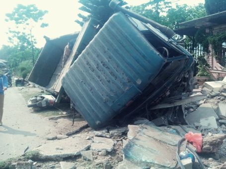 Chiếc xe ben sau khi cày nát tường rào đã bị lật nghiêng, đè lên xe mô tô