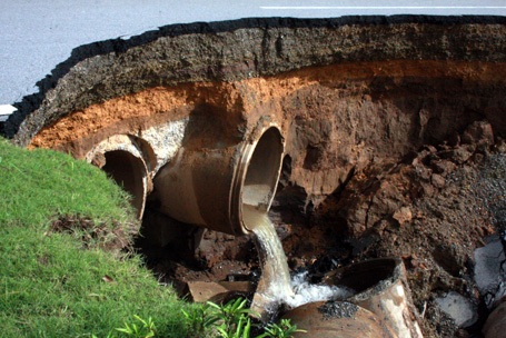 Nước vẫn chảy ra từ cống cắt ngang mặt đường đổ vào hố tử thần