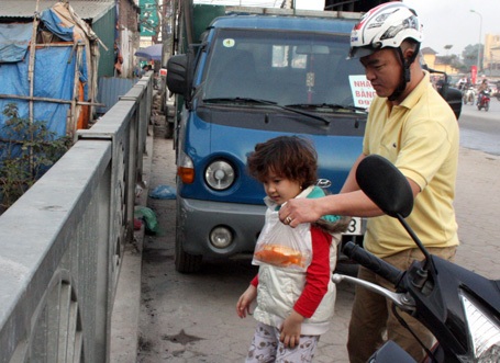 Các em bé đi theo bố mẹ đến nơi ngập rác