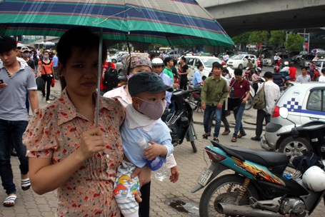 Các em nhỏ, uể oải đợi xe cùng người thân.