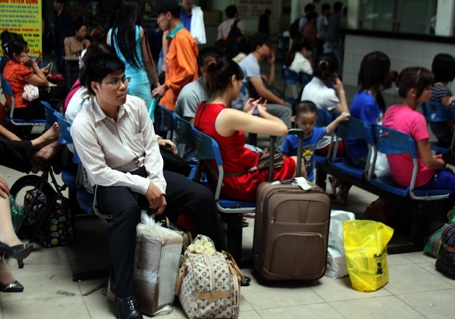 Các em nhỏ, uể oải đợi xe cùng người thân.