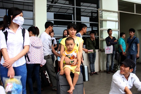 Các em nhỏ, uể oải đợi xe cùng người thân.