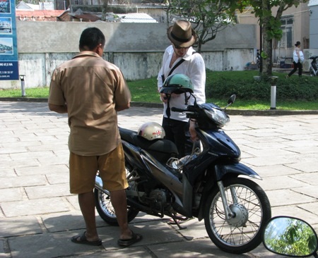 Một du khách nước ngoài đang kiểm tra xe thuê.