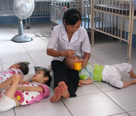 Nỗi lòng mấy chục năm nuôi con người khác - 2 Chị Xinh đang cho các bé bị bệnh bại não ăn chiều.
