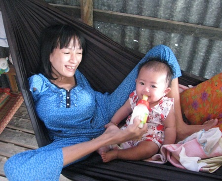 Em Nhung cho con bú sữa bình bên ngôi nhà cũ...