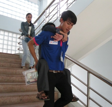 Trọng được tình nguyện viên Hiệp cõng lên xuống phòng thi.