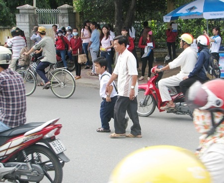 Nam sinh “tí hon” được cha dắt tay đi thi - 2 Nhân được cha dắt tay qua đường sau khi thi xong môn cuối sáng 5/7.