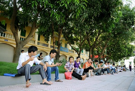 Phụ huynh ngồi hàng dài dưới bóng cây đợi con em