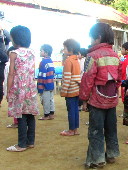 Một học sinh quần áo lấm lem bùn, áo rách tướp.