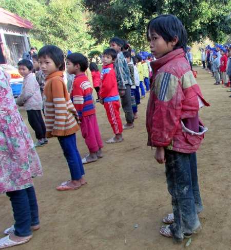 Một học sinh quần áo lấm lem bùn, áo rách tướp.