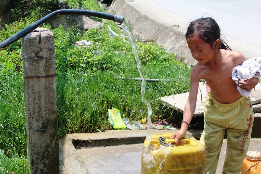 Em bé người dân tộc tranh thủ lúc đi lấy nước để
tắm “giải nhiệt”.