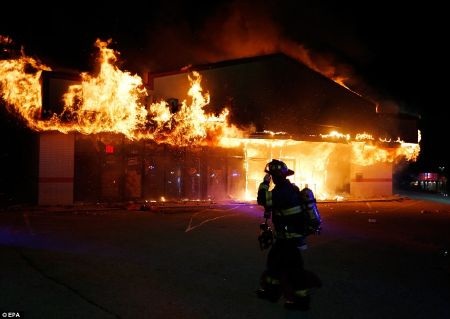 Một lính cứu hỏa đứng trước tòa nhà bị phóng hỏa đang cháy dữ dội