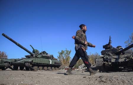 Một binh sỹ ly khai đi qua nhiều xe tăng bị phá hủy tại Donetsk (Ảnh: Tass)