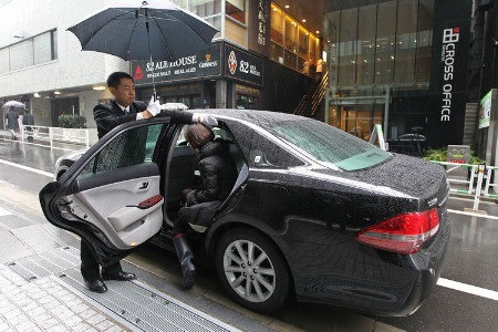 Nhật cấm cửa taxi Uber “ngay lập tức” - 1 Một lái xe mở cửa cho khách trong một đợt tập huấn ngoài trụ sở Uber Tokyo (Ảnh: