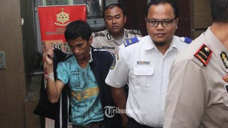 Mario Steven Ambarita (áo xanh) bị đưa đi thẩm vấn sau khi được chăm sóc y tế (Ảnh: Tribunnews)