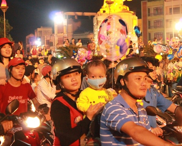 Các bậc phụ huynh đưa con em đi chơi đêm hội trăng Rằm. (Ảnh: Doãn Công)