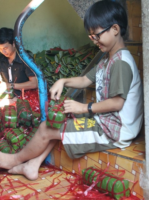 Em Nguyễn Quốc Thịnh tranh thủ được nghỉ Tết giúp mẹ cắt dây thừa trên bánh