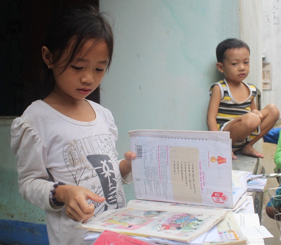 Em Nguyễn Dịu Linh HS lớp 2 trường tiểu học Phước Thuận (huyện Tuy Phước) phơi sách vở bị ướt