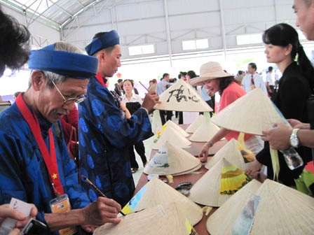 Các ông đồ cho chữ trên nón lá tặng du khách.