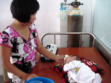 Chị Nhi lau mát giúp bé Minh Tú hạ sốt tại BV Nhi Đồng 1