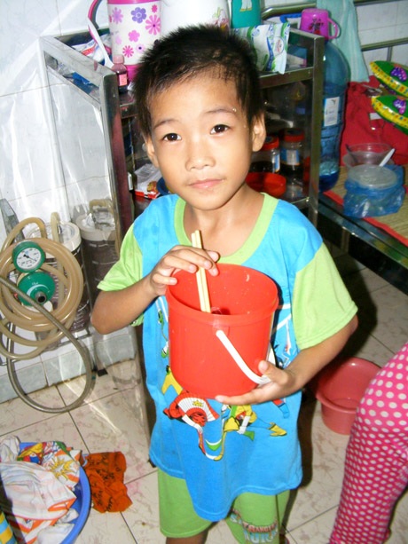 Hàng ngày, cháu Nguyễn Minh Tuấn mang hộp nhựa đi sang chùa và nhà dân gần bệnh viện để xin cơm